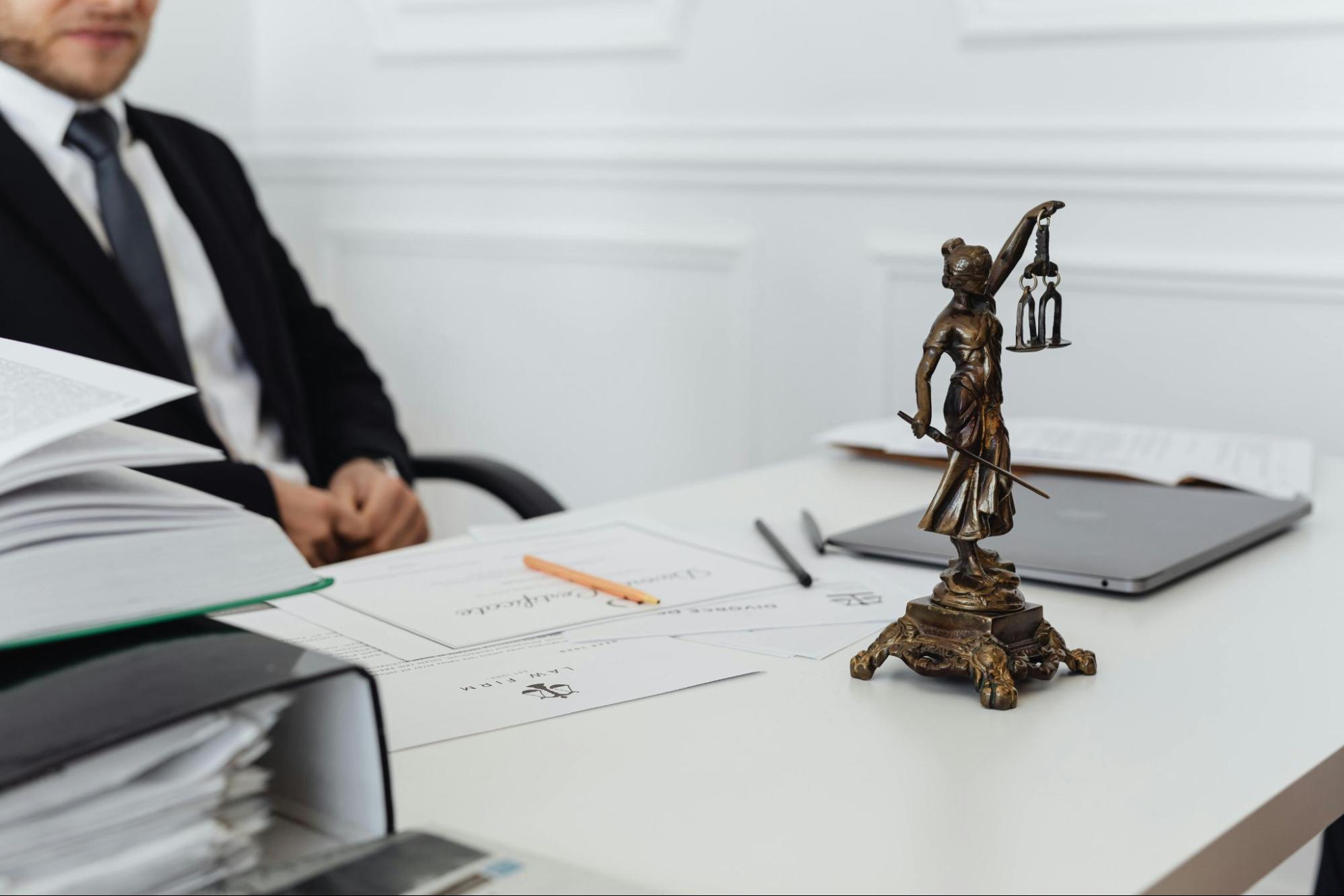 A person sitting at a desk with papers on it and a small bronze statue.