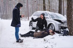 woman is lying on the snow after car crash