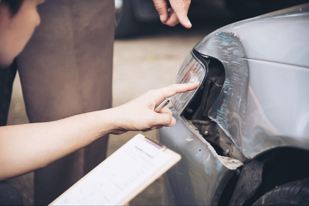 A person touching car’s broken headlight