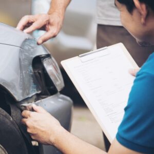 A man checking a car and holding a form